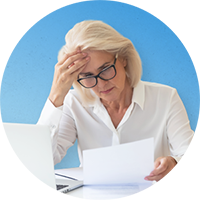 A concerned woman looking at her laptop and documents
